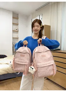 Vue détaillée du sac à dos scolaire rose à motif d'étoiles avec poche avant et pendentif.