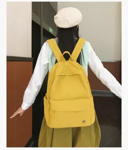 Détail de sac à dos d'école en toile jaune, sac décontracté avec poche avant et bretelles.