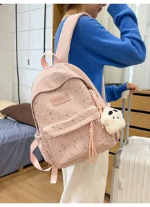 Vue détaillée du sac à dos rose à motif d'étoiles avec pendentif en peluche et poche avant.