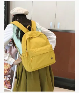 Vue détaillée du sac à dos scolaire jaune, montrant la scène de port et grande capacité.