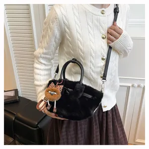 Detail view of stylish black plush bucket bag with cute pendant and comfortable strap.