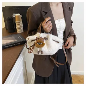 Detail view of winter plush pleated bucket bag with cute pendant, brown handle and strap.