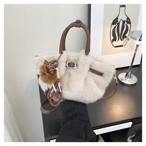 Detailed view of the plush pleated bucket bag with brown leather handles and cute furry charm.