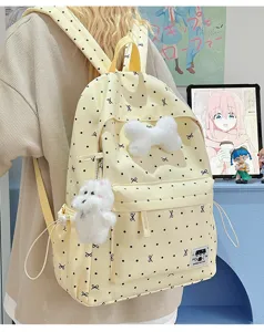 Süßer gelber Canvas-Rucksack mit Punkten, plüschigem Knochen-Anhänger und Hundemotiv im Detail.