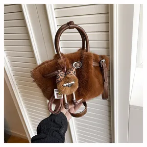 Detailed view of the brown plush pleated bucket bag featuring cute furry charm and dual handles.