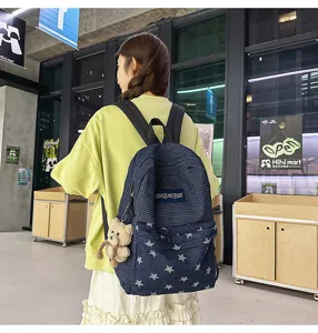 Large capacity student backpack with denim five-pointed star pattern and cute bear pendant.