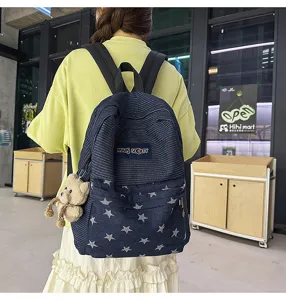 Detail view of the denim backpack featuring star patterns, contrast stripes, and a cute bear charm.