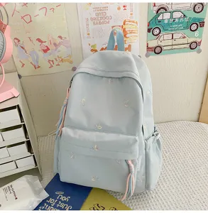Detalle de mochila escolar azul claro con bonitos lazos bordados de colores y tela duradera.