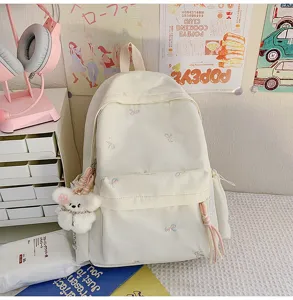 Detalle de mochila bonita bordada con lazos, bolsa escolar grande con colgante de osito.