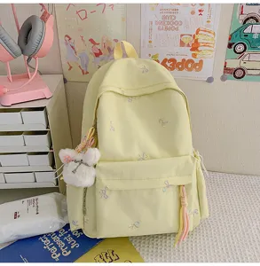 Bonita mochila escolar amarilla clara con bonito bordado de lazo y colgante de conejo peluche.