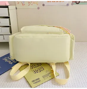 Vista cercana detallada de la mochila escolar amarillo claro con lindo lazo, mostrando la tela.