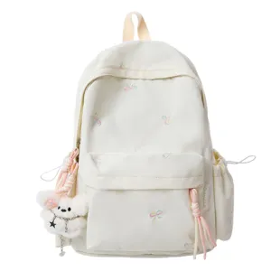Mochila escolar bordada con lazos, colgante de osito de peluche y bolsillos laterales.