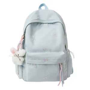Mochila escolar azul pastel con lazos bordados y llavero de conejito de peluche tierno.