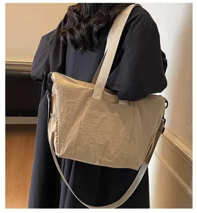 Detail shot of a large capacity beige nylon tote bag worn on shoulder, casual daily style.