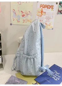 Vue detaillee du sac a dos scolaire bleu clair avec des motifs d'etoiles argentees.