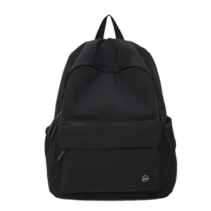 Sac à dos scolaire noir minimaliste en détail, tissu résistant avec une poche avant pratique.