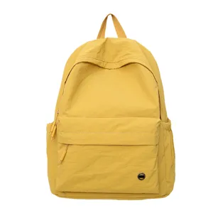 Détail de sac à dos jaune montrant un tissu en nylon durable, une poche avant et poignée.