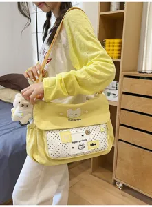 Cute canvas shoulder bag detail view, featuring sweet polka dot front pocket and plush bear pendant.