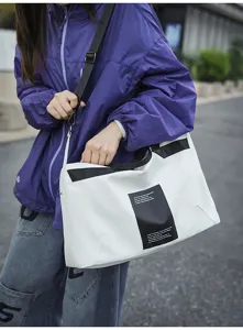 Bolso bandolera unisex blanco con correas negras, diseño moderno para viajes y uso diario.