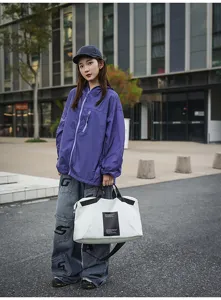 Bolsa de deporte blanca y negra duradera con asas y detalle de etiqueta frontal.