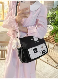 Cute black and white polka dot messenger bag for students, featuring a cat design and plush bear.