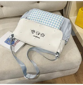 Vista detallada del bolso bandolera de cuadros azul claro con estampado de gato y correa.