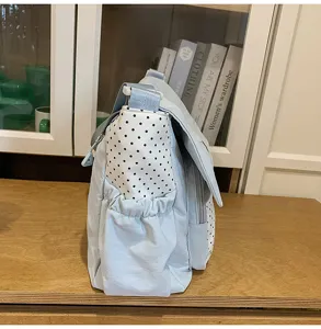 Detailed view of the cute blue shoulder messenger bag with black and white polka dot side pockets.