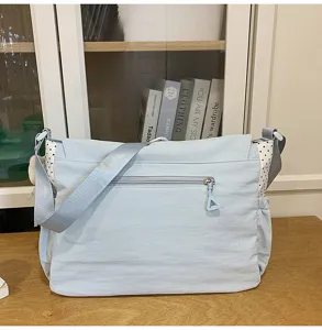 Light blue canvas shoulder bag detail, featuring contrast side pockets, zipper pocket and strap.