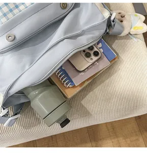 Detalle de bolso bandolera escolar de cuadros azul claro que muestra gran capacidad interior.