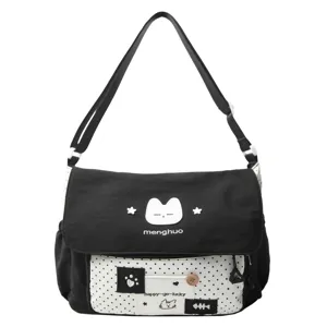 Detail view of black and white polka dot canvas messenger bag with cute cat design and strap.