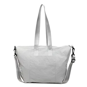 Detail view of grey nylon casual tote bag, featuring sturdy dual top handles and crossbody strap.