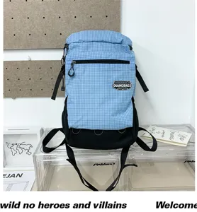 Détail de sac à dos à carreaux bleu avec poche avant zippée et écusson de la marque.