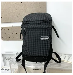 Vue détaillée du sac à dos à carreaux noirs avec poche avant et sangles solides.