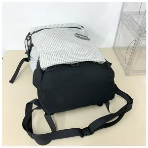 Vue détaillée du grand sac à dos à carreaux noir et blanc avec sangles réglables.