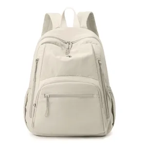 Sac à dos minimaliste en nylon beige avec plusieurs poches zippées pour le quotidien.