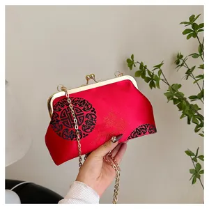 Detail view of red satin evening bag with gold chain and vintage Chinese embroidery.