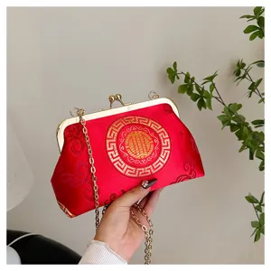 Close-up detail of the traditional Chinese style red brocade clutch bag with gold embroidery.