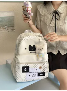 Vista detallada de la bonita mochila de lunares con bordado de gato y colgante de peluche.