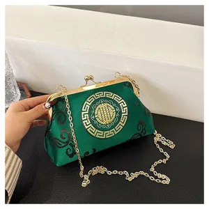 Green satin clutch bag detail featuring golden metallic frame and elegant traditional embroidery.