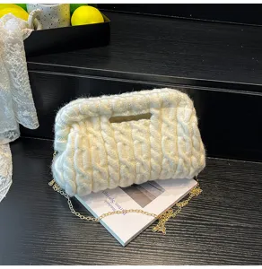 Gedetailleerde close-up van een stijlvolle witte gebreide clutch tas met gouden ketting.