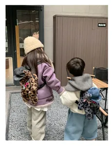 Detailaufnahme des niedlichen Plüsch Leo Bär Rucksacks, der von Kindern im Freien getragen wird.