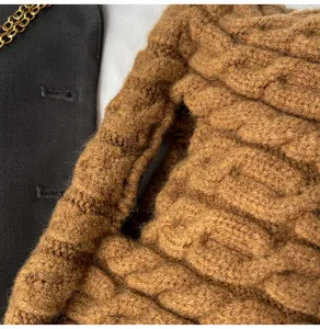 Detailopname van de bruine pluche gebreide tas textuur met een zacht kabelpatroon.