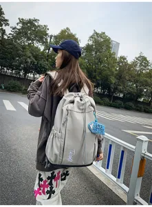 Vue détaillée du sac à dos de voyage avec tissu résistant et charm suspendu.