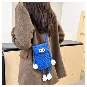 Detailed shot of cute blue knitted mobile phone bag with funny big eyes and long arms and legs.