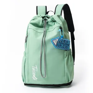Détail de sac à dos cordon vert clair montrant broderie avant et accessoire porte-clés.