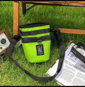Borsa a tracolla a secchiello verde alla moda con cinturini neri, design streetwear.