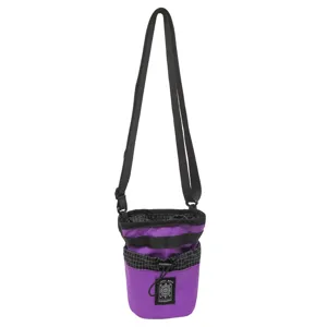Dettaglio della piccola borsa a tracolla viola con cinturino nero, bordo a quadretti e toppa.