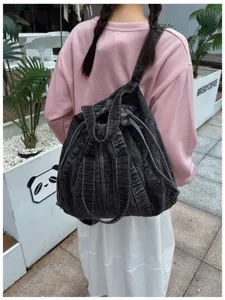 Vue arrière détaillée d'un sac à dos en denim lavé vintage avec des coutures épaisses.