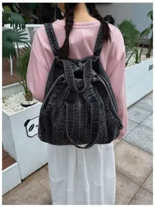 Vue détaillée du sac à dos en denim lavé gris foncé avec cordon de serrage et bretelles.