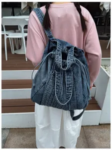 Detail du sac a dos en denim lave retro montrant la sangle multifonctionnelle et la fermeture.